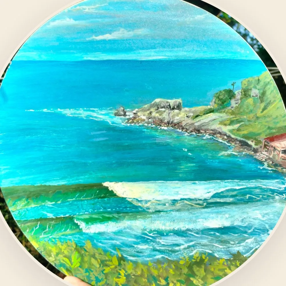 Round painting by Irving Silva: the sea seen from above, with waves and a rocky shore